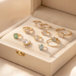 Coffret élégant contenant plusieurs bijoux de naissance en or, posés avec raffinement sur un tissu clair.
