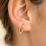 Gros plan sur l’oreille d’une femme portant de petites boucles d’oreilles hypoallergéniques au design minimaliste.